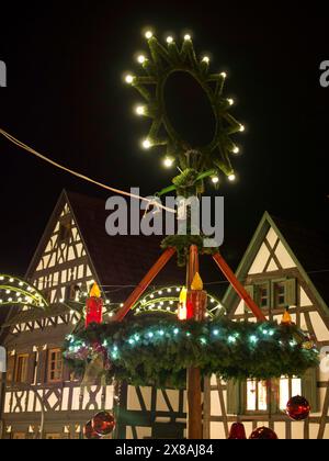 Beleuchteter Weihnachtskranz bei Nacht mit Fachwerkhäusern im Hintergrund, historische Kleinstadt mit Fachwerkhäusern und eine Kirche bei Chris Stockfoto