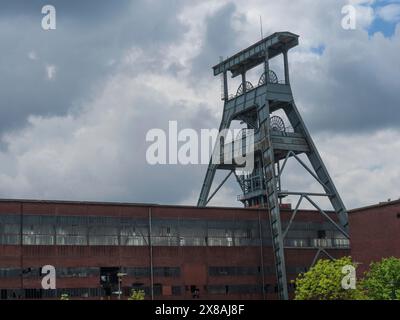 Detailansicht eines gewundenen Turms und eines alten Fabrikgebäudes unter bewölktem Himmel, Bergbauturm einer stillgelegten Zeche im grünen Ruhrgebiet, Herten, GE Stockfoto