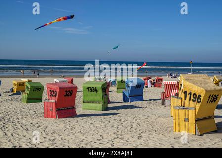 Bunte Liegen am Strand, mit Drachen am Himmel und ruhigem Meer im Hintergrund, bunte Liegen am Strand in der Sonne, Langeo Stockfoto