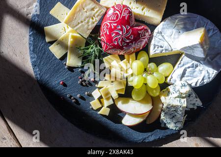 Käseplatte mit Trauben, Apfelscheiben und einem dekorativen Herz Stockfoto