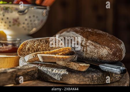 Frisch gebackenes Brot mit Scheiben auf einem rustikalen Tisch Stockfoto