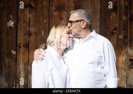 Senior Pärchen in weiß, die eine liebevolle Umarmung teilen Stockfoto
