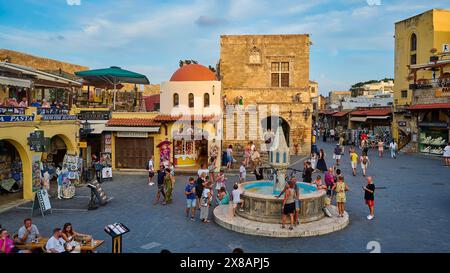 Hippokrates Square, Eulenbrunnen, lebendiger historischer Platz mit einem zentralen Brunnen, umgeben von mittelalterlicher Architektur und vielen Touristen an einem sonnigen Tag Stockfoto