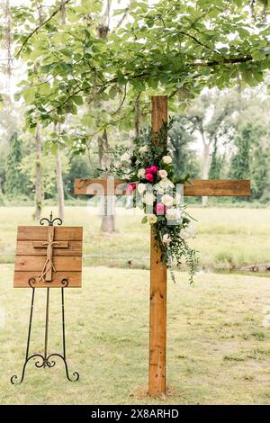 Holzkreuz mit Blumenarrangements im Freien Stockfoto