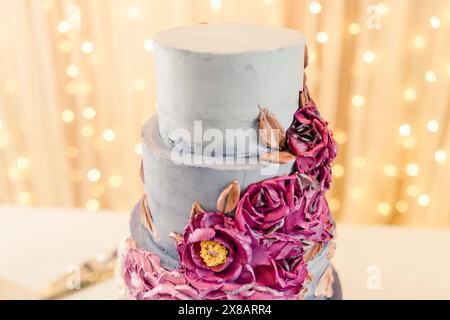 Elegante dreistufige Hochzeitstorte mit violetten Blumendekorationen Stockfoto