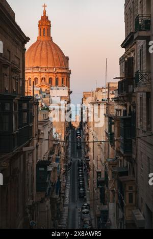 Die engen Gassen von Valletta bieten atemberaubende Architektur und einen Blick auf eine sehr orangene St. Paul's Cathedral Kuppel im Abendlicht Stockfoto