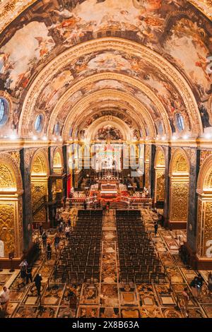 Blick vom Balkon der St. John's Co-Cathedral in Valletta, Malta, mit verziertem Interieur, Fliesenboden, Stühlen, und Besuchern Stockfoto