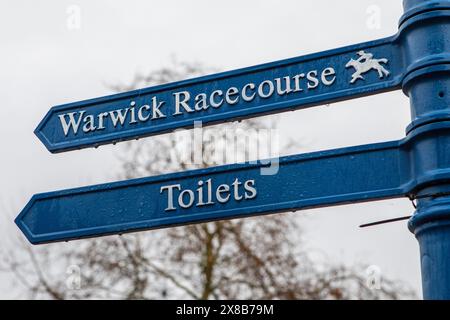 Wegweiser in der schönen Stadt Warwick, Großbritannien, die die Richtung Warwick Racecourse und lokale Toiletten zeigen. Stockfoto