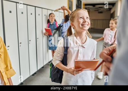 Eine Gruppe von Kindern mit unterschiedlichem Aussehen steht in einem Flur neben farbenfrohen Schließfächern. Stockfoto