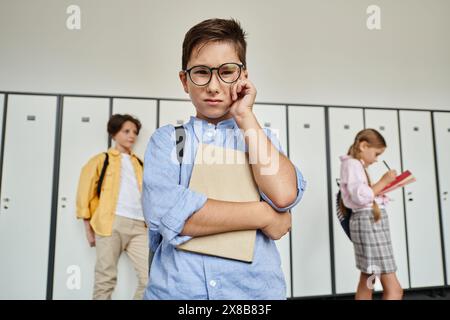 Ein Junge in einem blauen Hemd steht in Reihen von Schließfächern in einem Schulflur. Stockfoto