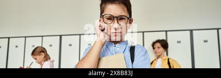 Ein Schuljunge in einem blauen Hemd steht in Reihen von Schließfächern in einem Schulflur. Stockfoto