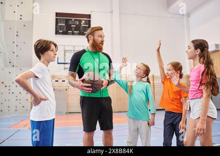 Ein dynamischer Lehrer steht vor einer Gruppe von Kindern in einem lebhaften Klassenzimmer, um sie zu motivieren und zu unterrichten. Stockfoto