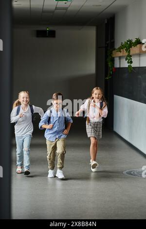 Eine Gruppe kleiner Kinder lacht und läuft durch einen Flur, voller Aufregung und Energie. Stockfoto