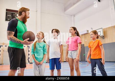 Ein Mann hält einen Basketball und führt eine vielfältige Gruppe von Kindern in einem lebhaften Klassenzimmer. Stockfoto