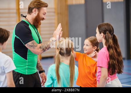 Ein männlicher Lehrer steht vor einer Gruppe verschiedener Kinder und unterrichtet sie in einem hellen, lebendigen Klassenzimmer. Stockfoto