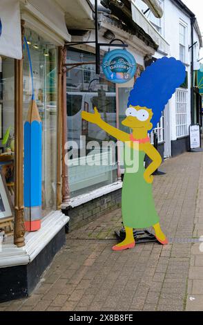 Großer Pappschnitt von Marge Simpson, der zur Blue Pencil Gallery in der Hauptstraße von Honiton, Devon, England, Großbritannien, winkt. Stockfoto