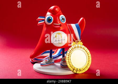 ZHONGSHAN China-23. Mai 2024: Das Maskottchen der Olympischen Spiele 2024 in Paris mit Goldmedaille auf rotem Hintergrund in horizontaler Komposition. Stockfoto