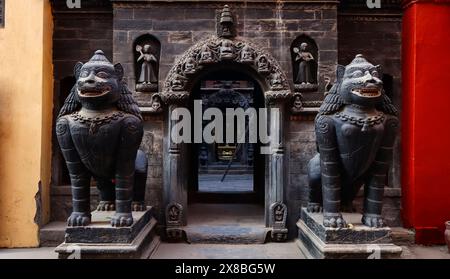 Geschnitzte Löwenstatue vor Hiranya Varna Mahavihar, Patan, Kathmandu, Nepal. Stockfoto