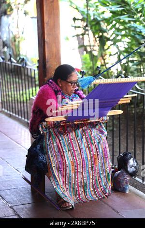 Indigene Maya-Frau, die einen Rückenriemen benutzt, um Stoff zu weben. Bunte Textilien von Hand, Antigua. Artesans von Guatemala Mittelamerika. Stockfoto