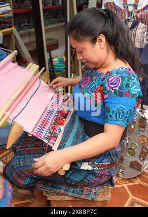 Indigene Maya-Frau, die einen Rückenriemen benutzt, um Stoff zu weben. Bunte Textilien von Hand, Antigua. Artesans von Guatemala Mittelamerika. Stockfoto