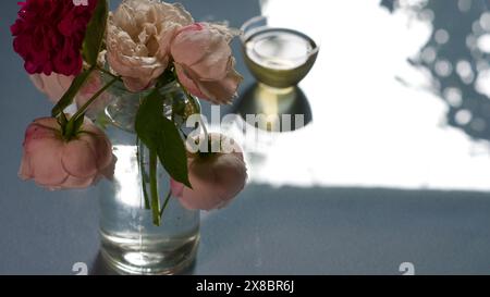 Eine Glasvase mit Rosen und einer kleinen Schüssel grünem Tee. Das Konzept der Ruhe. Stockfoto