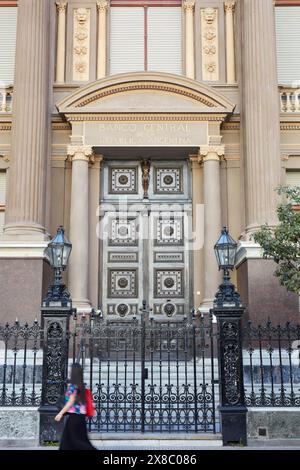 Eine Frau, die an der Fassade der argentinischen Zentralbank vorbeifährt (BCRA oder Banco Central de la Republica Argentina, Microcentro, Buenos Aires, Argentinien). Stockfoto