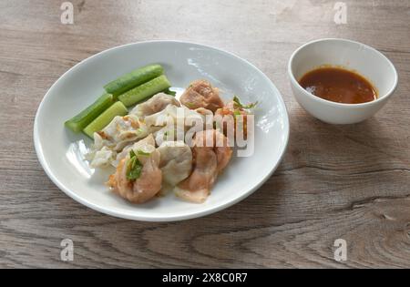 Gedünsteter Fisch und Garnelenknödel garnieren knusprig gebratenen Knoblauch mit Gurke auf Teller, mit würziger und saurer Sauce Stockfoto