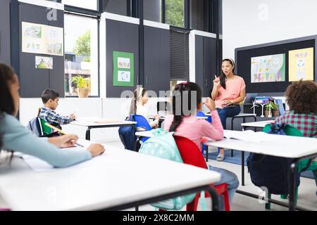 In der Schule, in einem Klassenzimmer, erklärt eine junge birassische Lehrerin eine Lektion Stockfoto