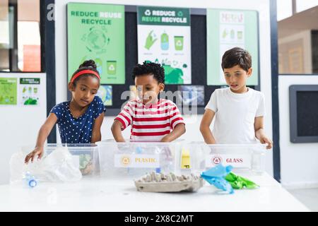 In der Schule sortieren verschiedene junge Schüler Recyclingmaterialien im Klassenzimmer Stockfoto