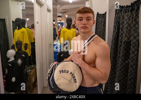 CREMONA, ITALIEN - 11. APRIL 2021: Fotoshooting eines jungen Models, das mit einer Sporttasche in einem Geschäft für die Marke Fred Perry posiert. Fred Perry ist Engländer Stockfoto