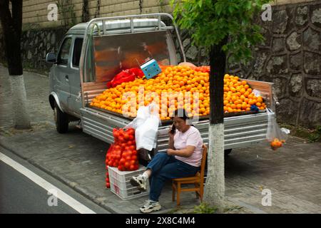 Lebensstil traditionelle chinesische Leute Hawker Stand auf LKW Auto Verkauf Citrus sinensis Mandarine Früchte auf Straßenbasar Markt für Leute se Stockfoto