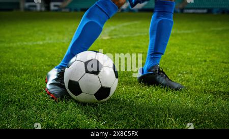 Nahaufnahme eines Beins in einem Schuh, der den Fußballball kickt. Profi-Fußballspieler trifft mit heftiger Kraft, erzielt Tor, Gras fliegt. Football Championship-Konzept. Künstlerische Aufnahme Mit Niedrigem Winkel. Stockfoto