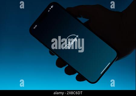 New York, USA – 6. Mai 2024: Öffnen Sie die Disney Plus App auf dem Smartphone in Hand isolierter blauer Farbverlauf Stockfoto