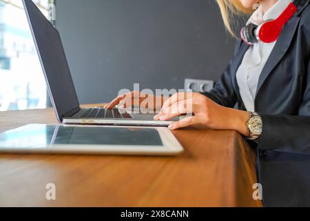 Eine Frau im Business-Anzug sitzt mit einem Laptop an einem Schreibtisch. Moderne Geschäftsfrau, die im Büro mit Laptop arbeitet Stockfoto