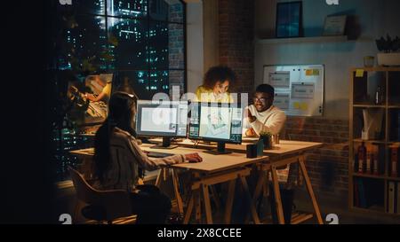 Kleine, vielfältige multiethnische Gruppen arbeiten an einem Projekt zusammen und arbeiten nachts in einem Büro zusammen. Teamleiter spricht mit einem Experten, lacht, diskutiert Änderungen an einem Softwaredesign. Stockfoto