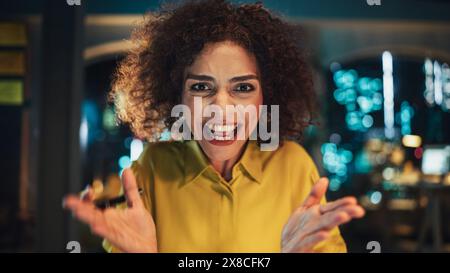 Blickwinkel aus der Kamera mit dem schönen multiethnischen arabischen Projektmanager, der nachts vom Büro aus ein Videogespräch führt. Ausdrucksstarke Spezialistin, die mit Kollegen über eine Live-Kamera spricht. Stockfoto