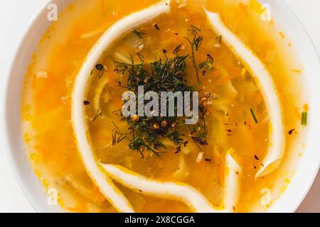 Eine weiße Schüssel gefüllt mit köstlicher Hühnersuppe garniert mit Kräutern und Mayonnaise. Stockfoto