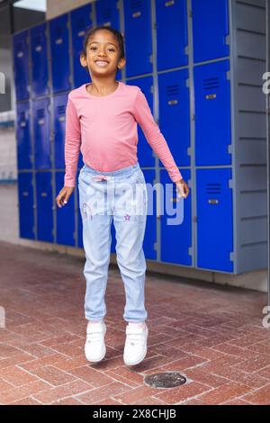 In der Schule steht ein junges birassisches Mädchen mit lässiger Kleidung Stockfoto