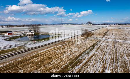 Ein Blick aus der Vogelperspektive auf Eine ländliche Landschaft mit Einem Teichhaus und schneebedeckten Feldern. Stockfoto