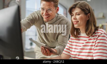 Porträt zweier kreativer Kollegen, die mit Computer und Tablet über die Arbeit sprechen. White Male Brand Manager Consulting Young Female Caucasian Creative Director. Nahaufnahme. Stockfoto