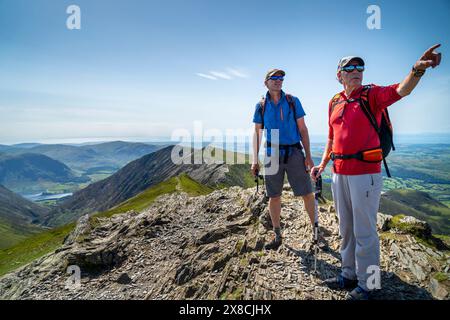 Ein Sommertag auf der Whiteside Ridge im Lake District - ein männlicher Wanderer weist einem jüngeren Mann auf ein entferntes Merkmal hin. Blick zurück auf den Bergrücken. Stockfoto