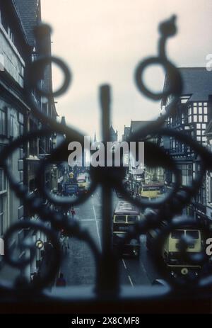 1975 Archivbild mit Blick nach Westen entlang der Eastgate Street, Chester, durch das Schmiedewerk der Eastgate Bridge und des Uhrturms. Stockfoto