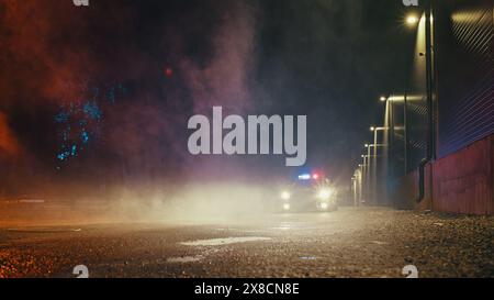 Niedrigwinkelaufnahme eines angehaltenen Polizeiautos mit Lichtern und Sirene während einer nebeligen Nacht. Patrouilliertes Fahrzeug im Bereitschaftsdienst, wartet auf Befehle, um Verdächtige zu verfolgen. Polizeivollstreckung Stockfoto