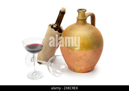 Glas mit Rotwein, eine Flasche und eine Vintage-Kanne isoliert auf weißem Hintergrund. Stockfoto