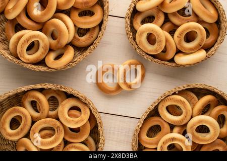Mehrere leckere Bagels in Strohplatten auf einem Holztisch, Nahaufnahme, Blick von oben. Stockfoto