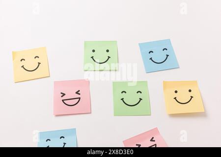 Farbenfrohe Stickernotizen mit Smiley-Gesicht an der weißen Wand Stockfoto