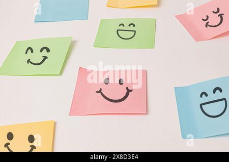 Farbenfrohe Stickernotizen mit Smiley-Gesicht an der weißen Wand Stockfoto
