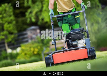 Landschaftler belüftet Rasen mit einem Benzinbelüfter in einem Wohnhof an einem sonnigen Tag. Stockfoto