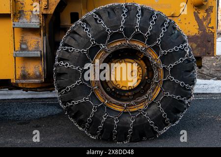 Schneeketten auf dem Rad eines Schneepflugs in den kalifornischen Bergen, die ein Rutschen auf vereisten Straßen beim Freiräumen von Schnee verhindern. Stockfoto