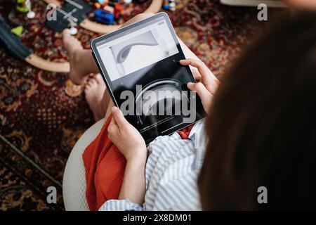 London, Großbritannien – 11. Juni 2023: In einem gemütlichen Wohnzimmer erkundet eine Frau die wichtigsten Funktionen des Apple Vision Pro Mixed-Reality-Headsets auf ihrem iPad Pro Stockfoto